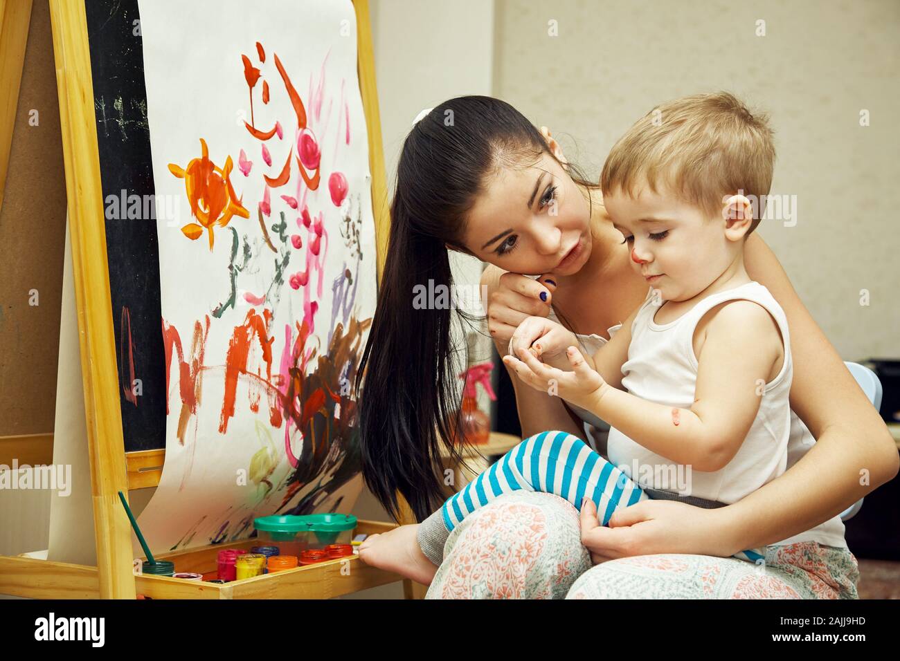 un petit garçon avec une mère peint un pinceau sur un chevalet. peinture de l'enfant. Banque D'Images
