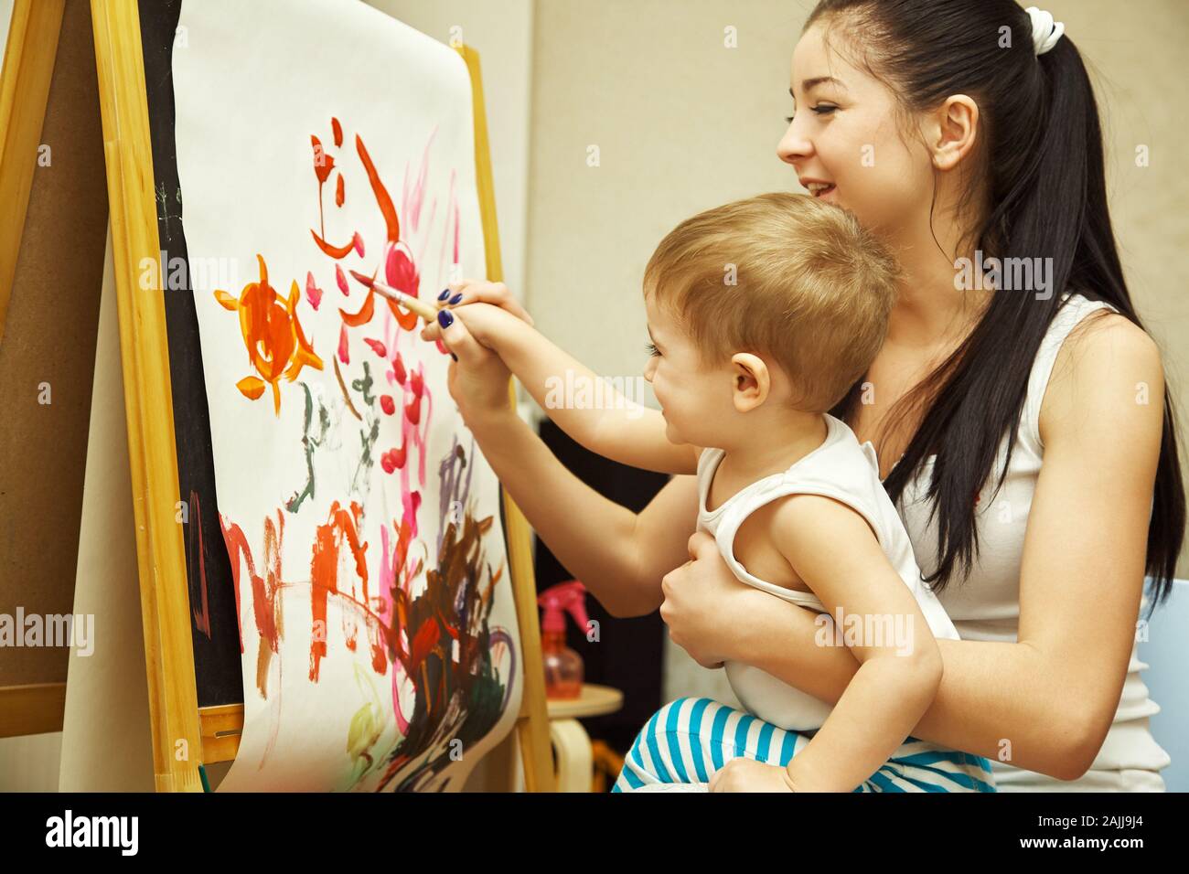 un petit garçon avec une mère peint un pinceau sur un chevalet. peinture de l'enfant. Banque D'Images
