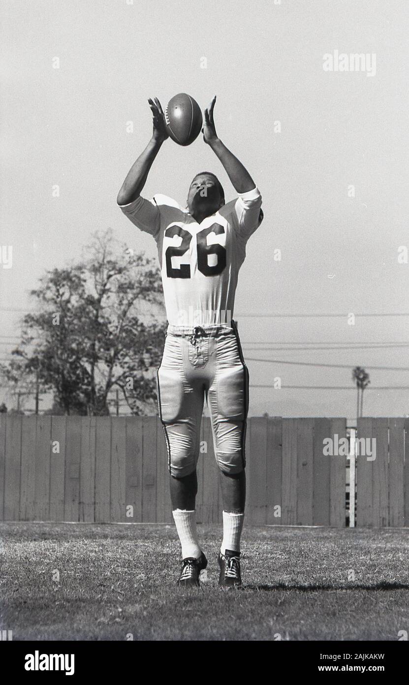 1964, historiques, football américain, homme college student practicising à l'extérieur avec la balle , USA. Banque D'Images