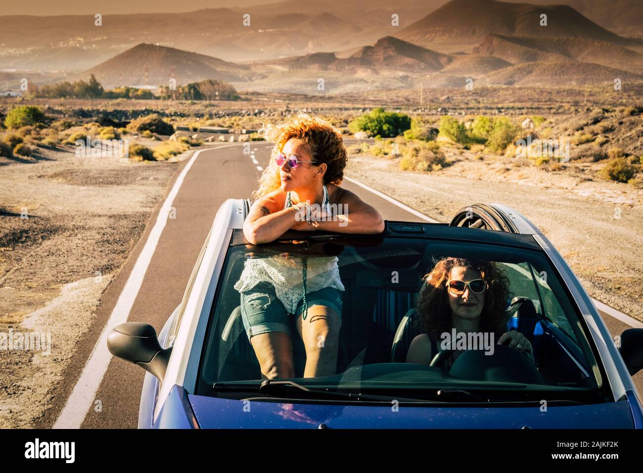 Couple d'amis femmes adultes voyageant ensemble gratuitement et indépendant sur une voiture avec mountsins convertivle et sauvage nature désert en fond - trave Banque D'Images