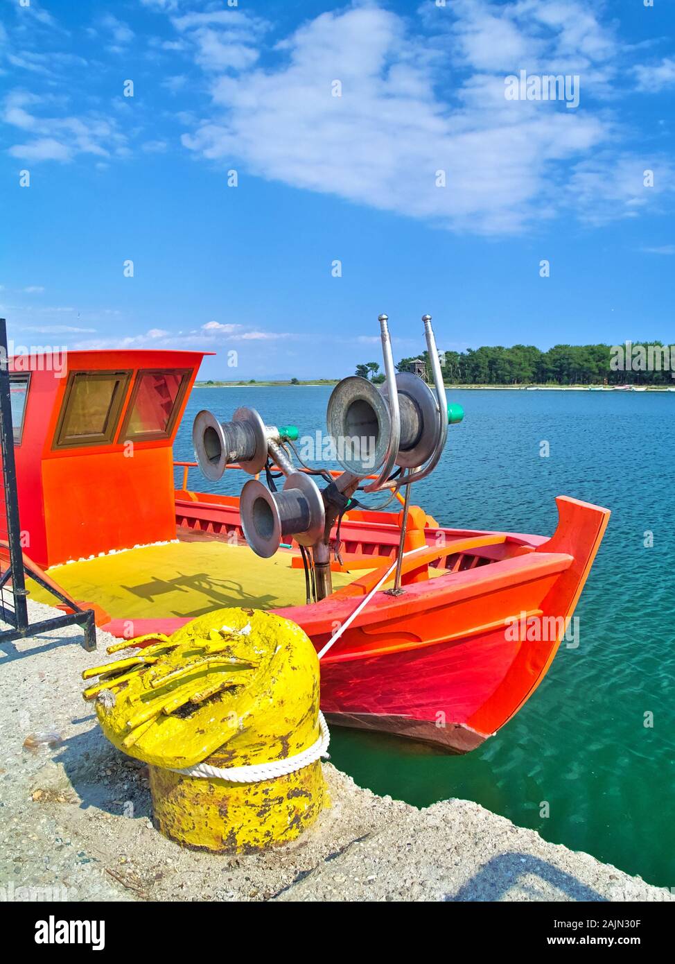 Porto Lagos, Grèce, frais peint orange vif et jaune bateau cordage métallique sous ciel bleu avec des nuages. Banque D'Images