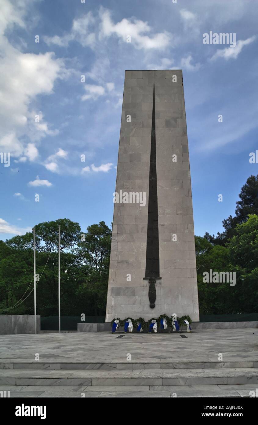 Monument de la Seconde Guerre mondiale et des guirlandes à Komotini, est de la Macédoine, la Grèce. Hauteur impressionnante tour en pierre avec une épée. Banque D'Images