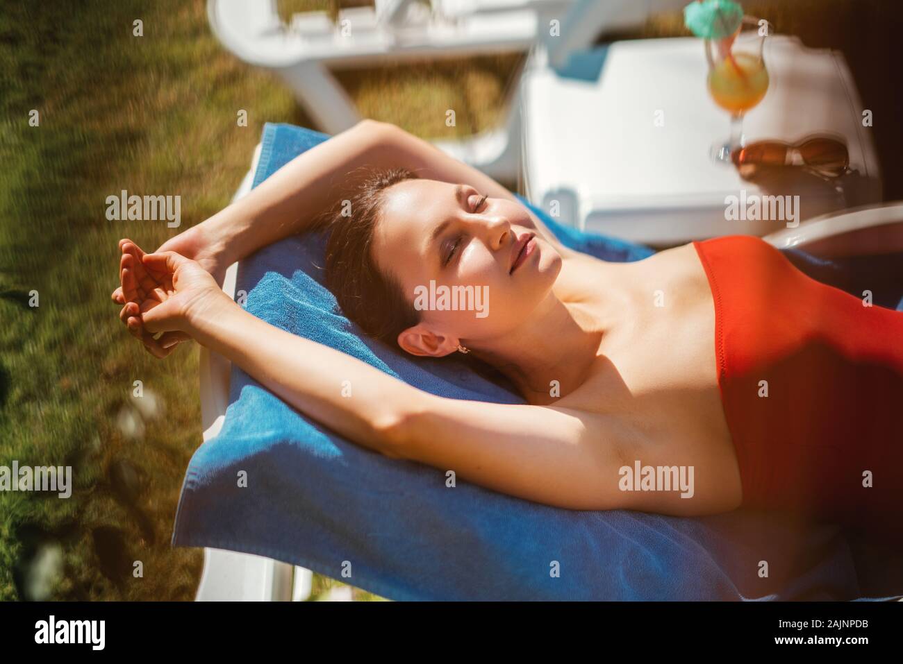 Jeune femme, bronzer et se détendre sur un transat dans sa maison de vacances. Banque D'Images