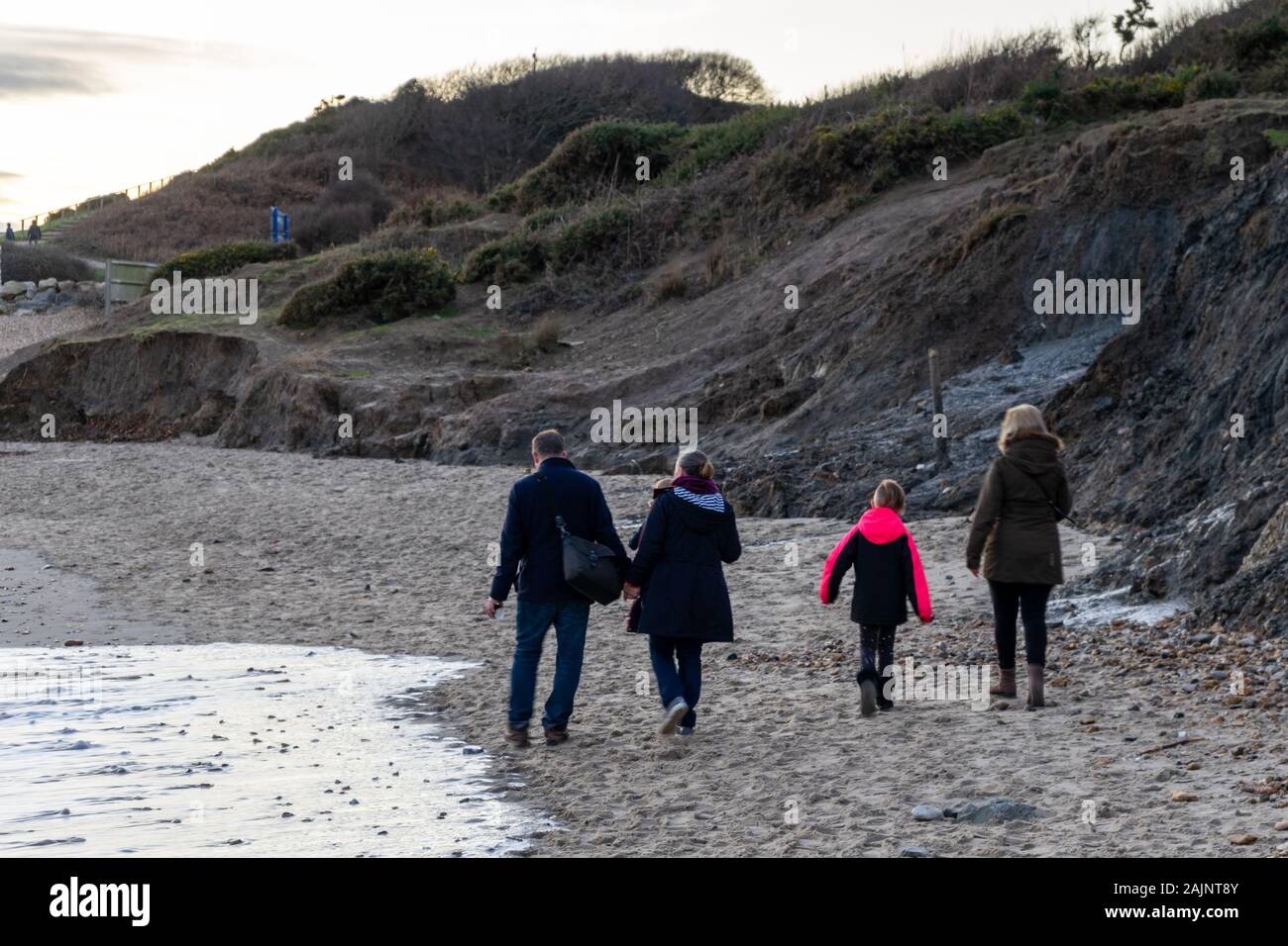 Une famille qui fait une promenade d'hiver le long de la plage de Highcliffe une plage de sable à Dorset Banque D'Images