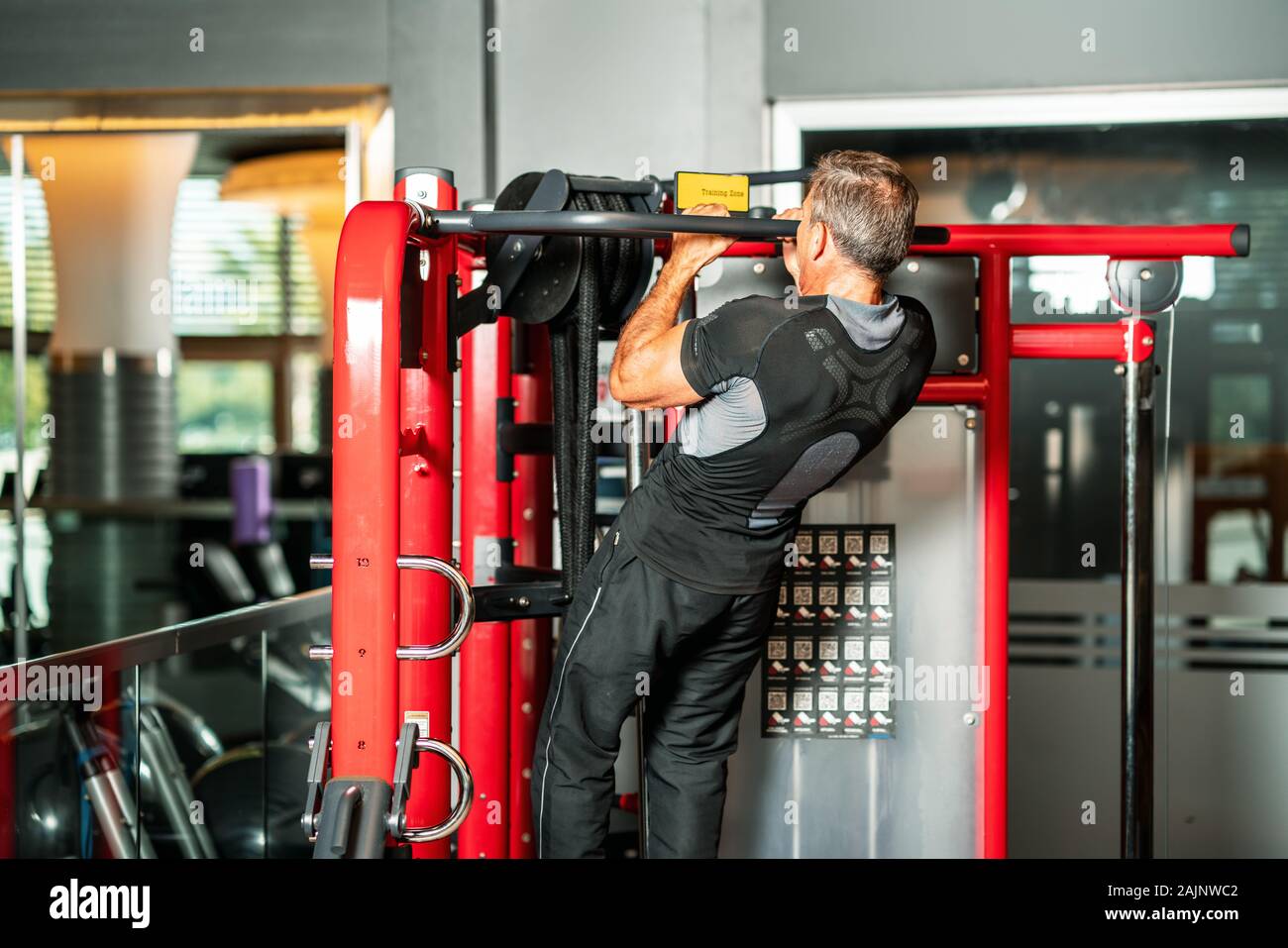 L'homme le renforcement de ses muscles en faisant tirer sur la barre horizontale dans un centre de remise en forme. Banque D'Images