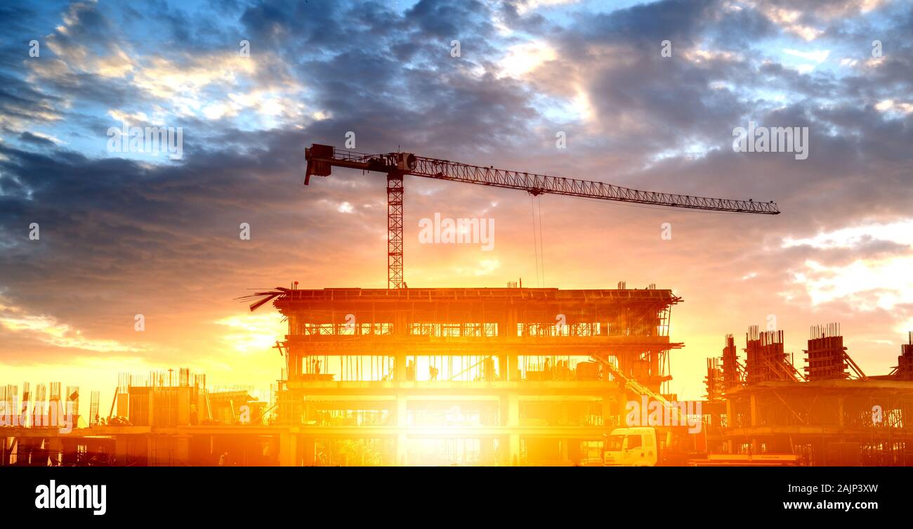 Silhouette d'un bâtiment avec une grue de construction contre les nuages. Banque D'Images