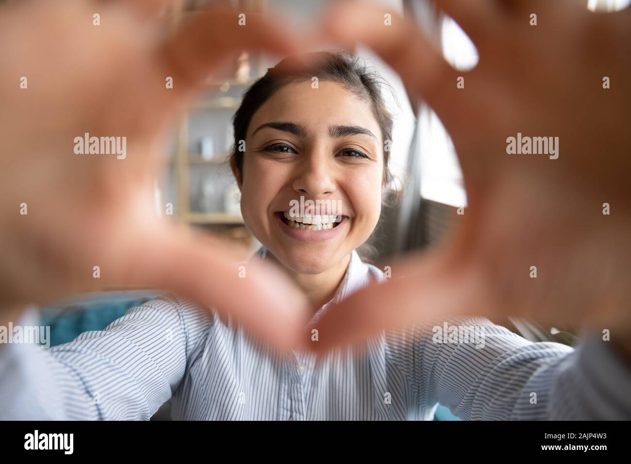 Cute happy indian girl making heart shape looking at camera Banque D'Images