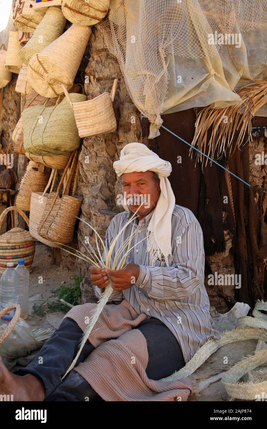 Panier et sac de fabrication travaillant à l'extérieur de son stand à l'entrée de l'oasis de montagne de Chebika Banque D'Images