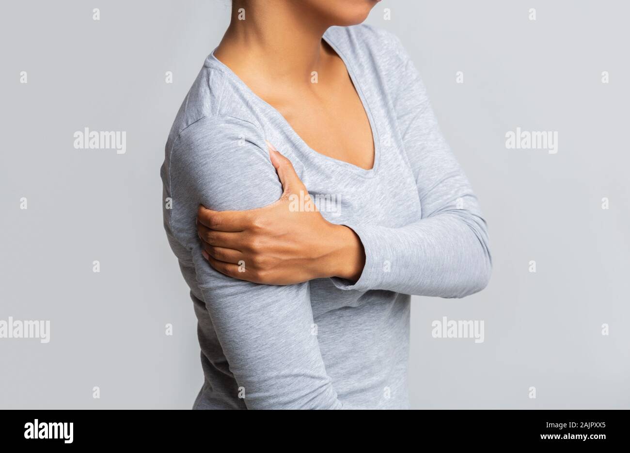 Portrait de femme noire tenant son avant-bras sur fond gris, ayant ...