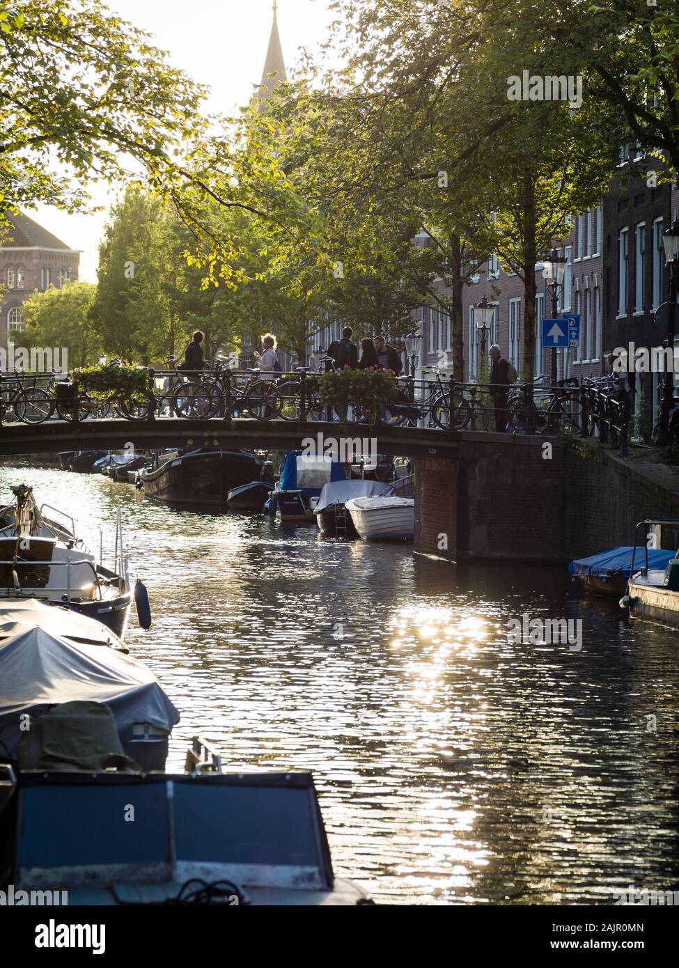 Soirée paisible scène avec les gens qui passent un pont sur Amsterdam et l'Bloemgracht néerlandaise de la vieille ville de Jordaan. Banque D'Images