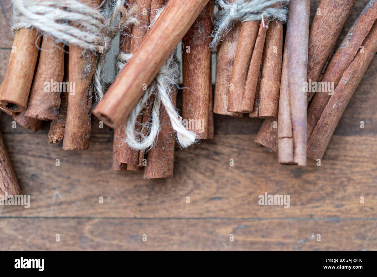 Les bâtons de cannelle et de repas close up sur fond de bois. Bordure décorative de Noël de bâtons de cannelle épice. Vue d'en haut. Banque D'Images