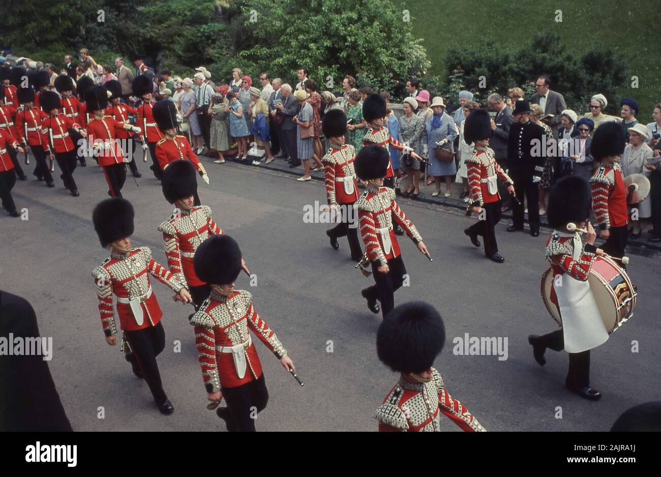 Années 1960, historique, spectateurs regardant la Queen's Guard et le groupe de marchage à l'ordre le plus noble du Garter, à l'extérieur du château de Windsor, Windsor, Angleterre, Royaume-Uni. L'ordre le plus noble du Garter a été fondé par le roi Édouard III d'Angleterre en 1348 et est l'ordre le plus élevé de Knighthood dans le système des honneurs britanniques. Banque D'Images