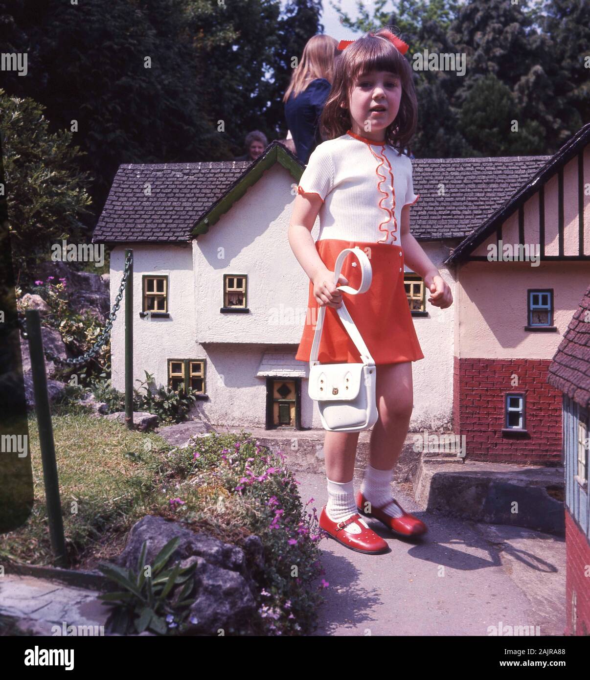 Années 60, historique, jeune fille avec un sac à main visitant un village  modèle, une collection de modèles à petite échelle de différents types de  bâtiments disposés comme un village anglais typique,