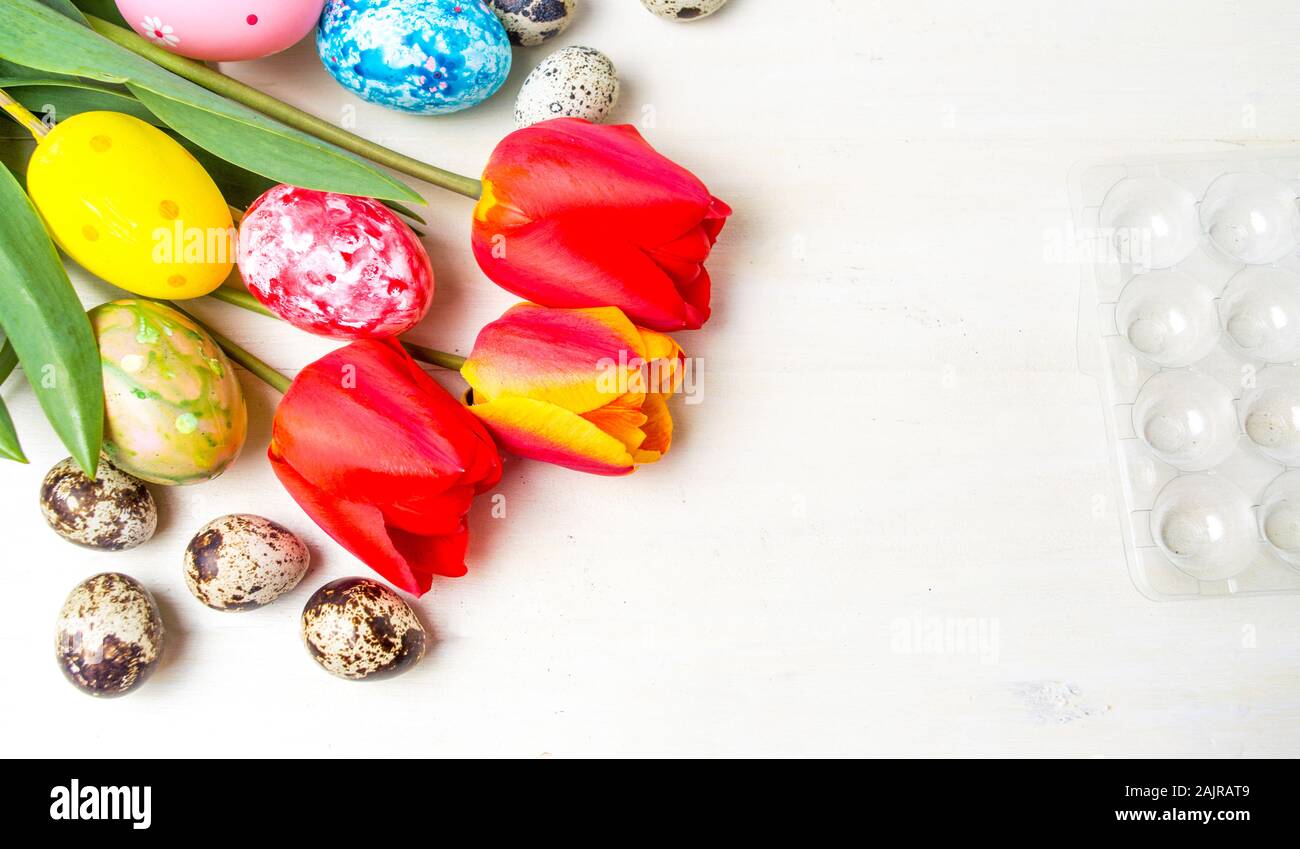 Tulipes rouges et les oeufs de Pâques sur table en bois Banque D'Images