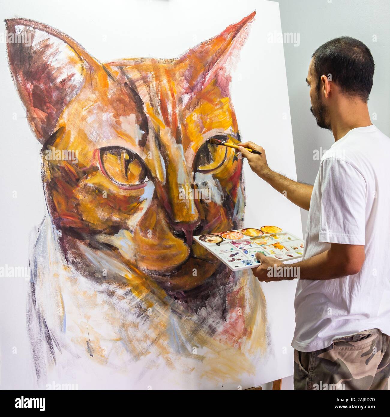 Un artiste asiatique portrait peinture acrylique gingembre cat, couleur sur toile blanche. Banque D'Images