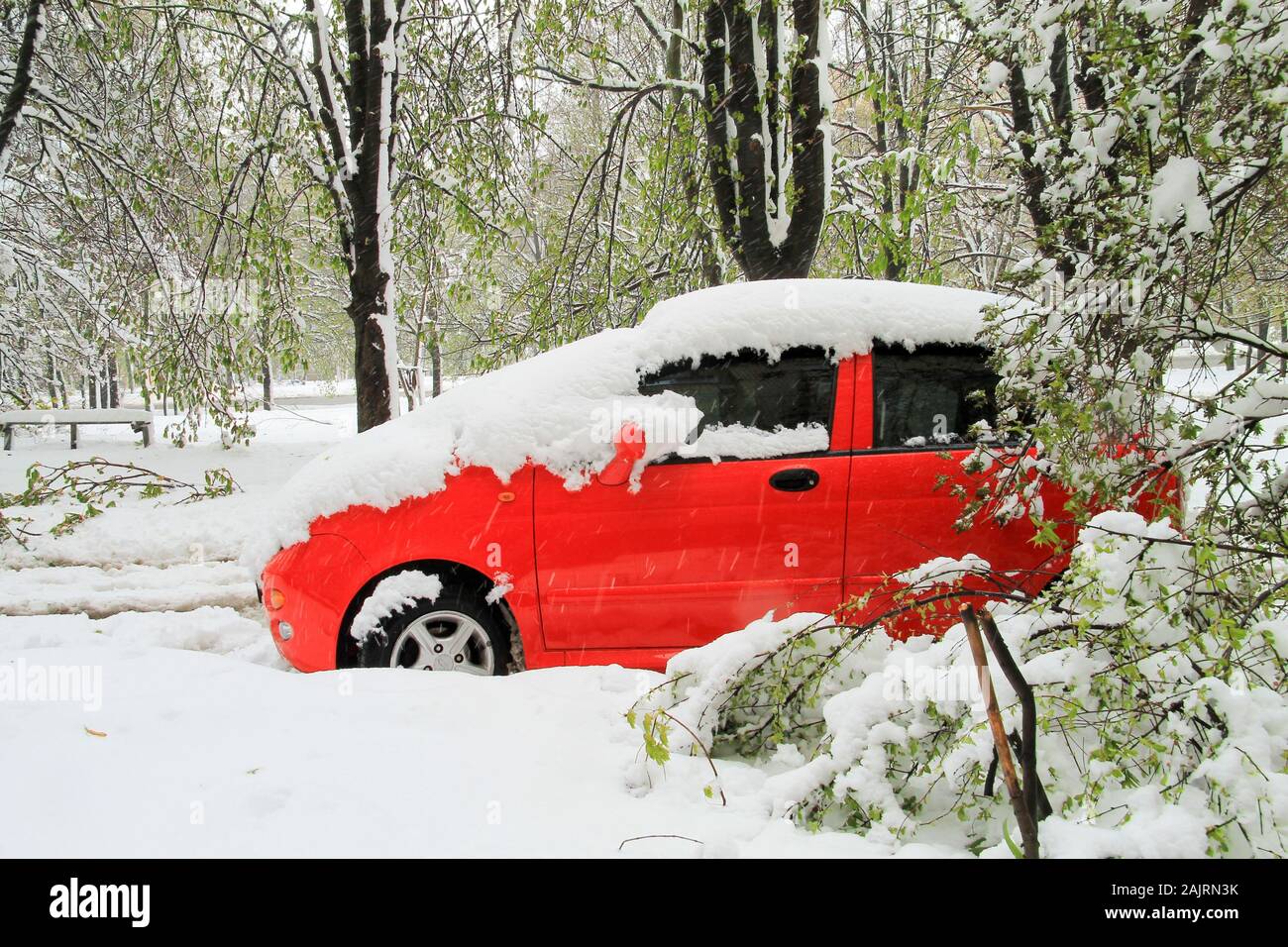 Ville de Dnipro, Ukraine, 19 04 2018. Une voiture rouge vif couvert de neige est stationné en présence de vent de l'hiver Banque D'Images
