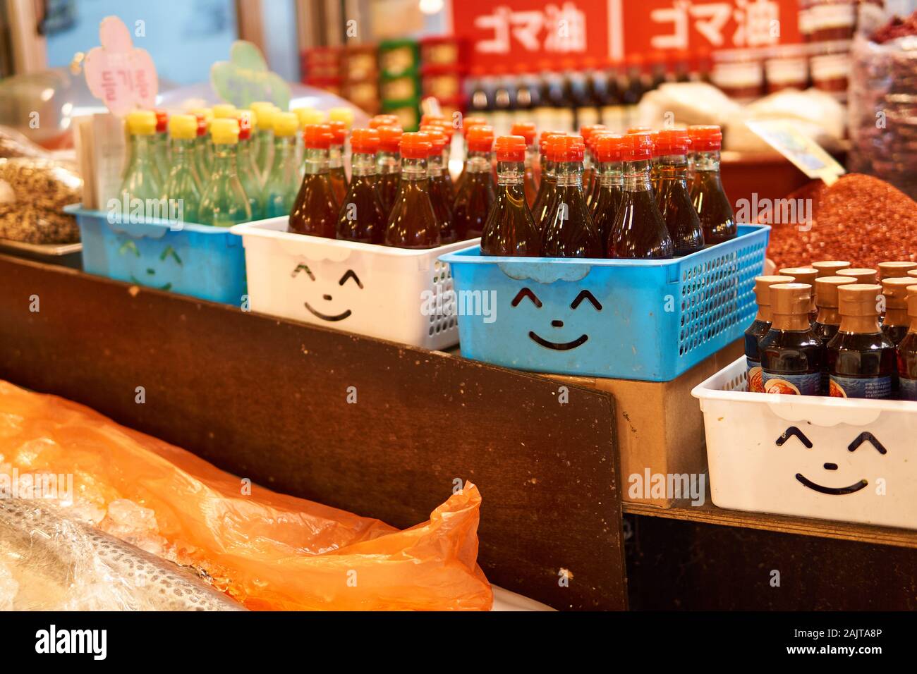 Des paniers en plastique bleu et blanc avec des visages émoiji souriants se coupent dans eux en tenant des sauces au marché de Gwangjang à Séoul, en Corée du Sud. Banque D'Images