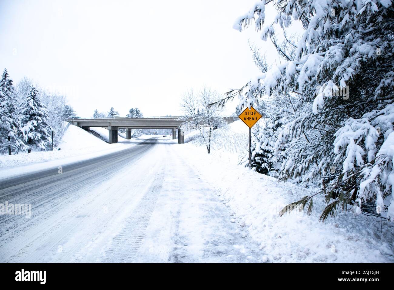 Route couverte de neige glissante et forêt dans le centre du Wisconsin en décembre avec arrêt à venir signer Banque D'Images