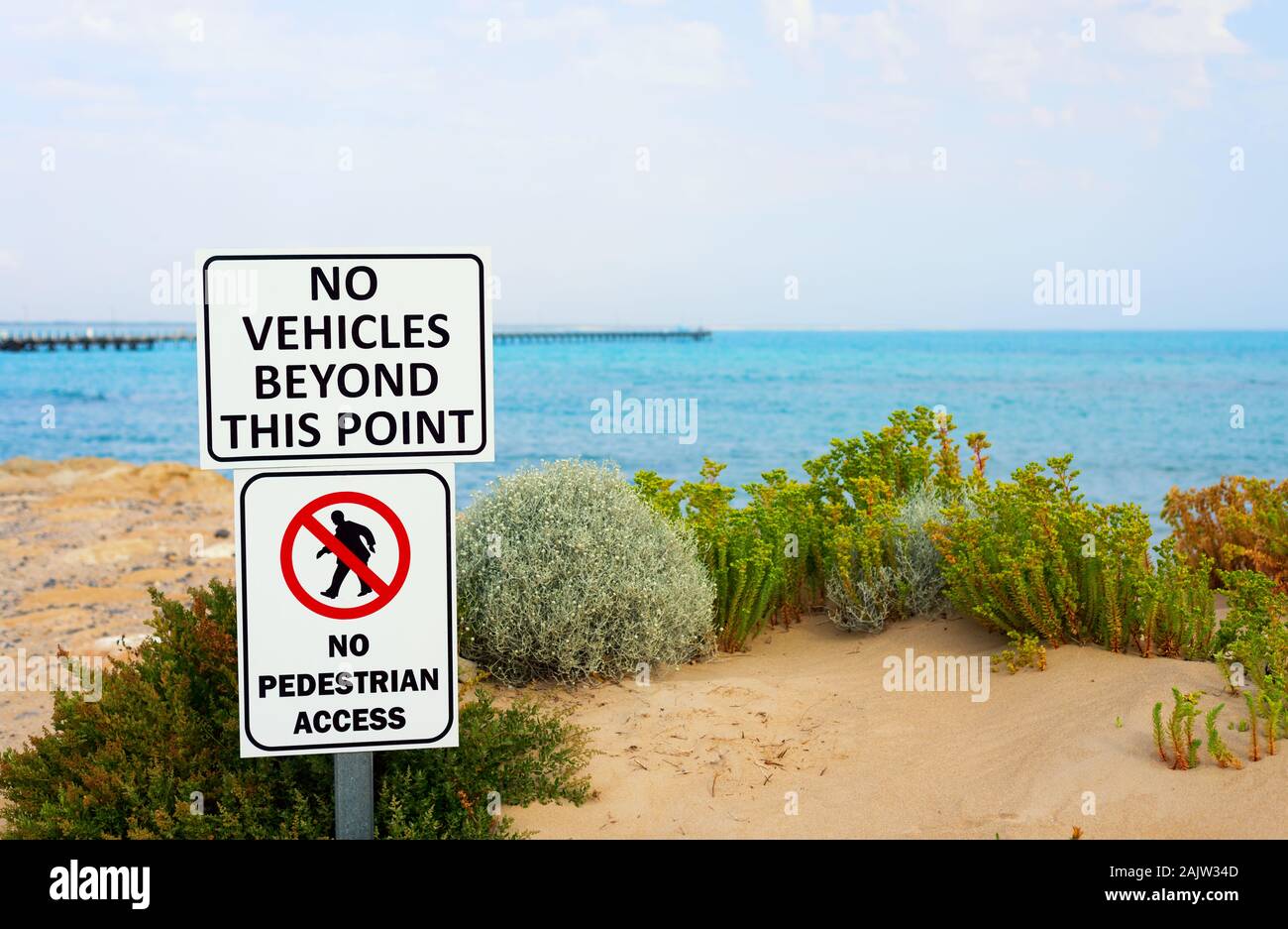 Une photo de 'Aucun véhicule au-delà de ce point' et 'pas d'accès piétons' signes sur une plage. Flou artistique sur la longue jetée en arrière. Banque D'Images