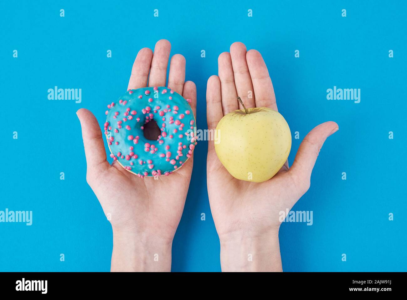 Le choix de la femme entre Apple et donut dans ses mains. Concept d'aliments sains Banque D'Images