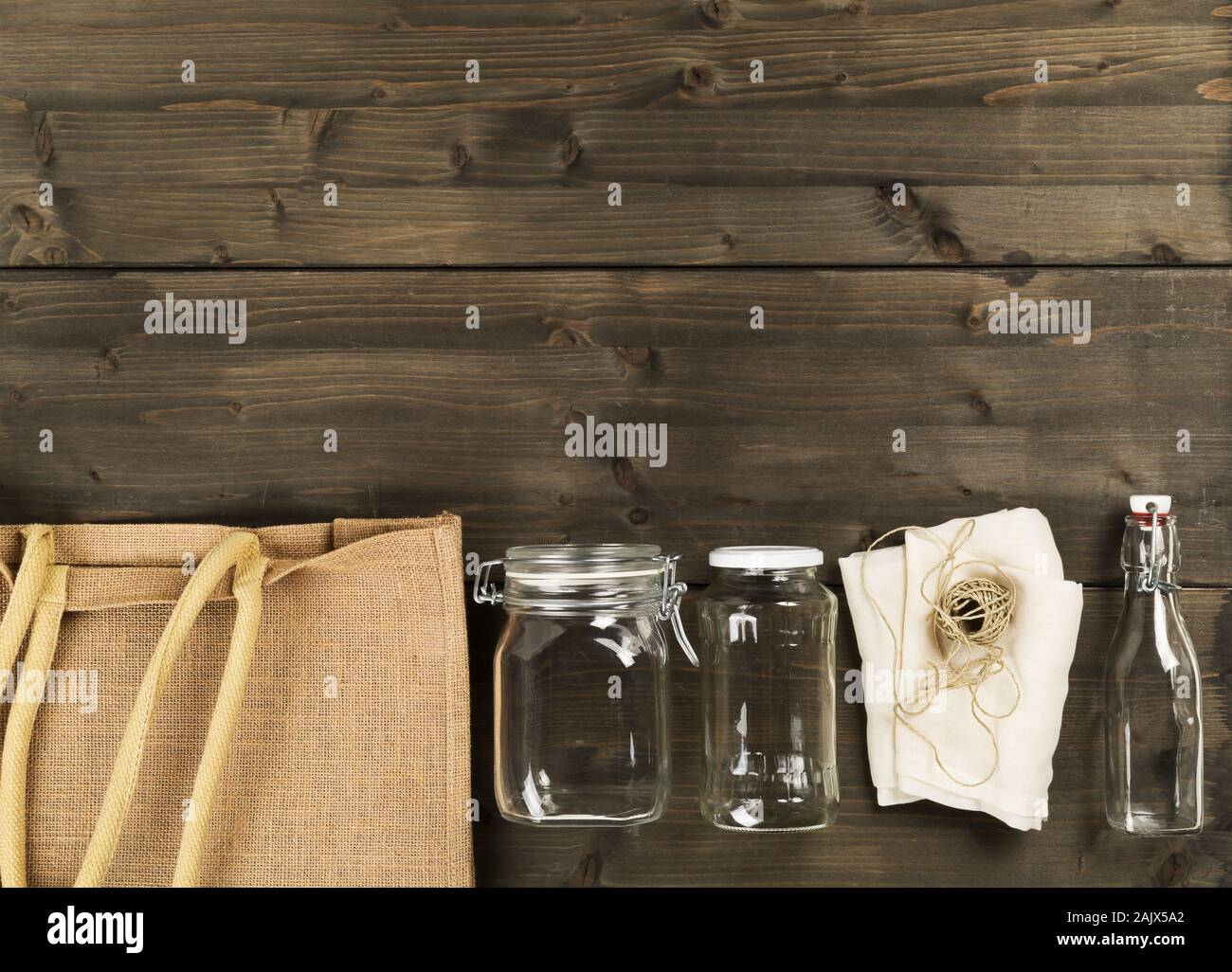 Zéro Déchets déchets ou free shopping ustensiles avec sac de toile, des bouteilles en verre et sac de coton sur fond de table en bois brun de poser à plat au-dessus - Déchets Banque D'Images