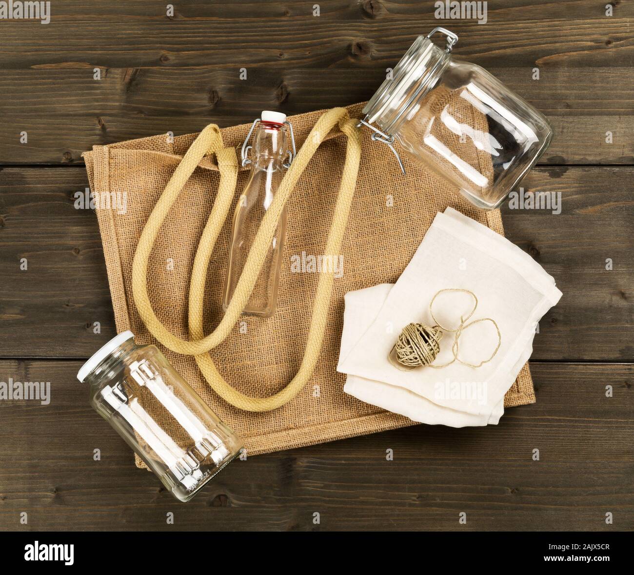 Zéro Déchets déchets ou free shopping ustensiles avec sac de toile, des bouteilles en verre et sac de coton sur fond de table en bois brun de poser à plat au-dessus - Déchets Banque D'Images