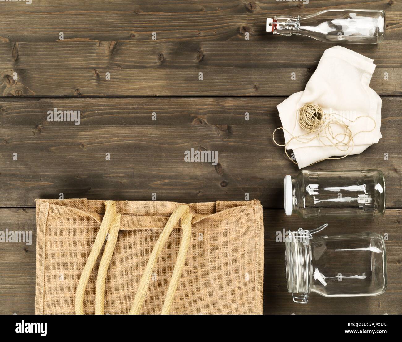 Zéro Déchets déchets ou free shopping ustensiles avec sac de toile, des bouteilles en verre et sac de coton sur fond de table en bois brun de poser à plat au-dessus - Déchets Banque D'Images