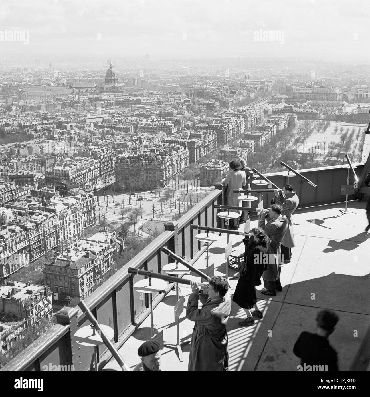 Années 1950, historiques, les gens à l'aide de télescopes pour voir à travers la capitale française en haut d'une galerie d'observation sur le célèbre monument, la Tour Eiffel, Paris, France. Une fois achevé en 1889, le réseau était le monument le plus haut du monde et l'est resté jusqu'en 1929. Banque D'Images