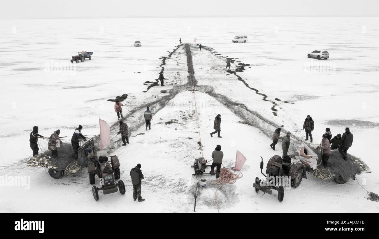 Les travailleurs chinois tirer un immense filet de pêche de s'attendre à une bonne récolte sur le lac de Wolong gelés dans le comté de Kangping, Shenyang, ville du nord-est de la Chine a Liaon Banque D'Images