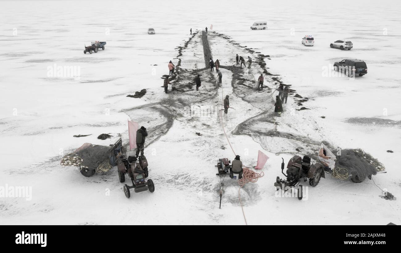 Les travailleurs chinois tirer un immense filet de pêche de s'attendre à une bonne récolte sur le lac de Wolong gelés dans le comté de Kangping, Shenyang, ville du nord-est de la Chine a Liaon Banque D'Images