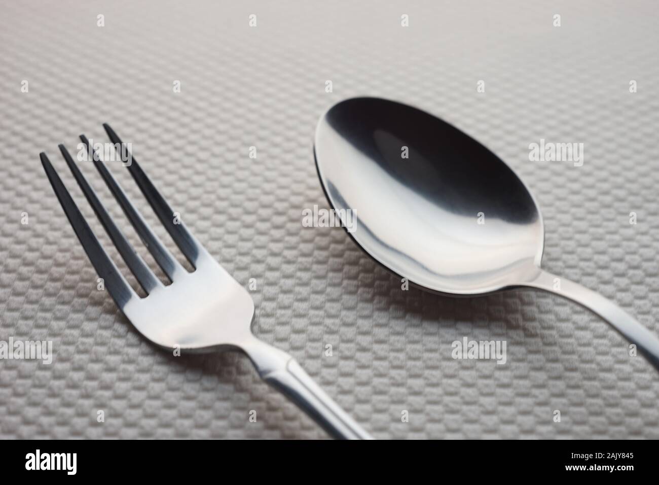 Acier inoxydable argenté moderne fourchette et cuillère sur une table avec une nappe blanche. Banque D'Images