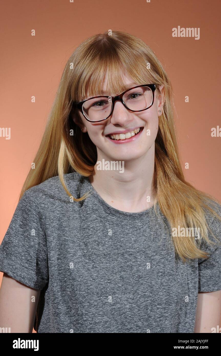 Jolie blonde woman wearing black lunettes encadrées et un t-shirt gris isolé sur un fond gradué Banque D'Images