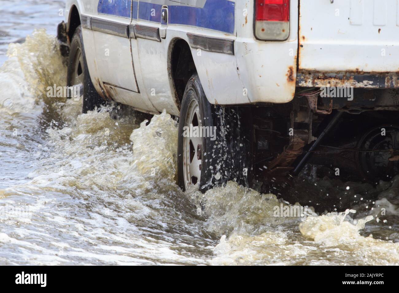 Les éclaboussures de voiture par une grande flaque sur une rue inondée Banque D'Images