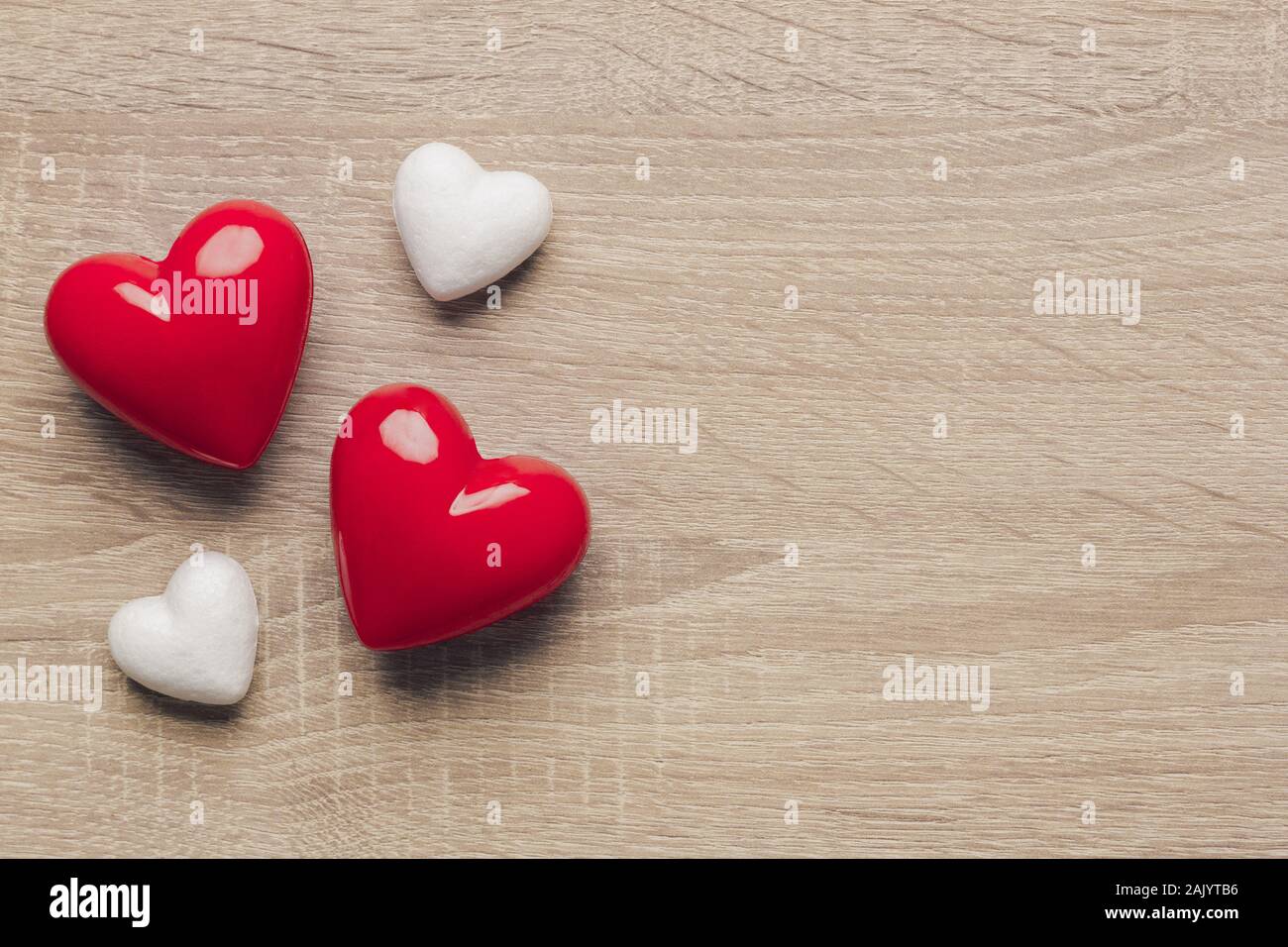 Stock photo de deux coeurs en plastique rouge et blanc deux cœurs sur un fond de bois. Le cœur sur le côté gauche avec un espace réservé au texte Banque D'Images