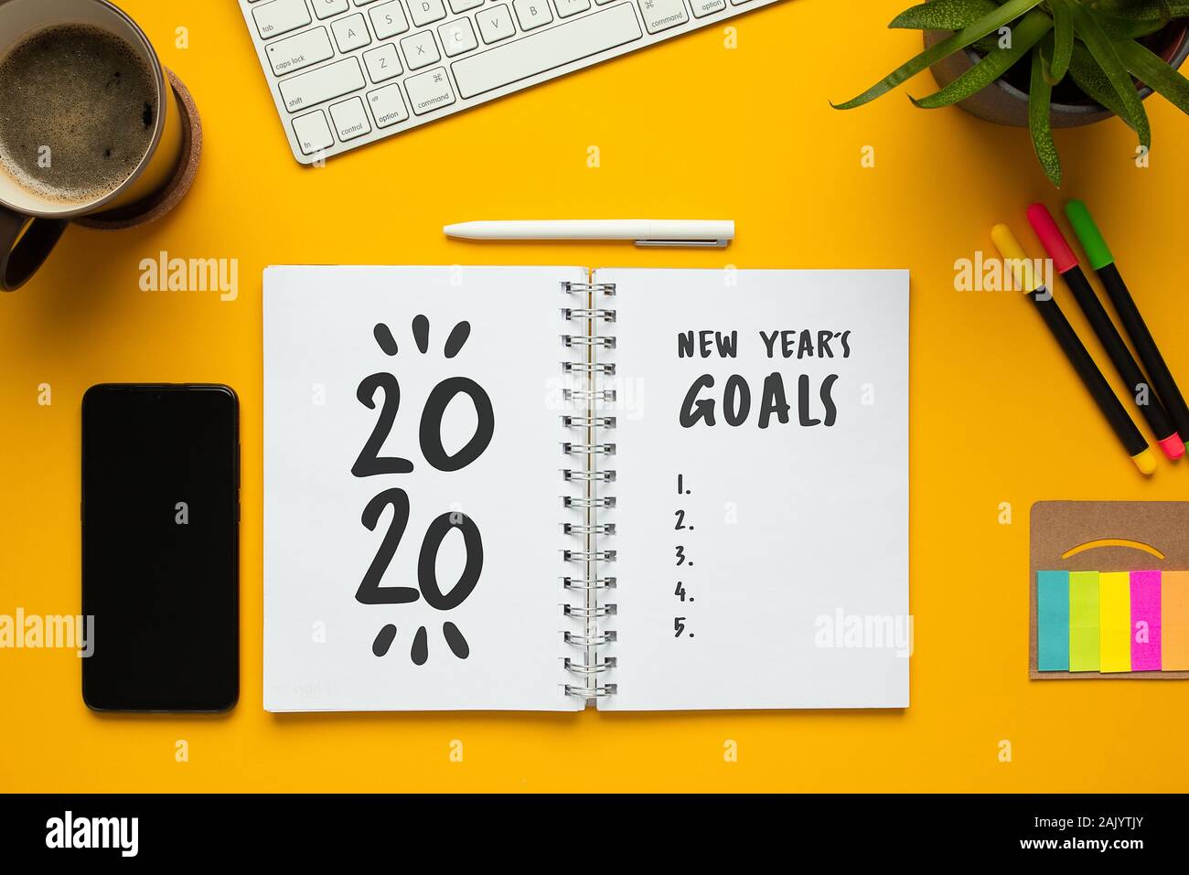 Stock photo de nouvel an 2020 portable avec liste d'objectifs et des objets sur fond jaune Banque D'Images