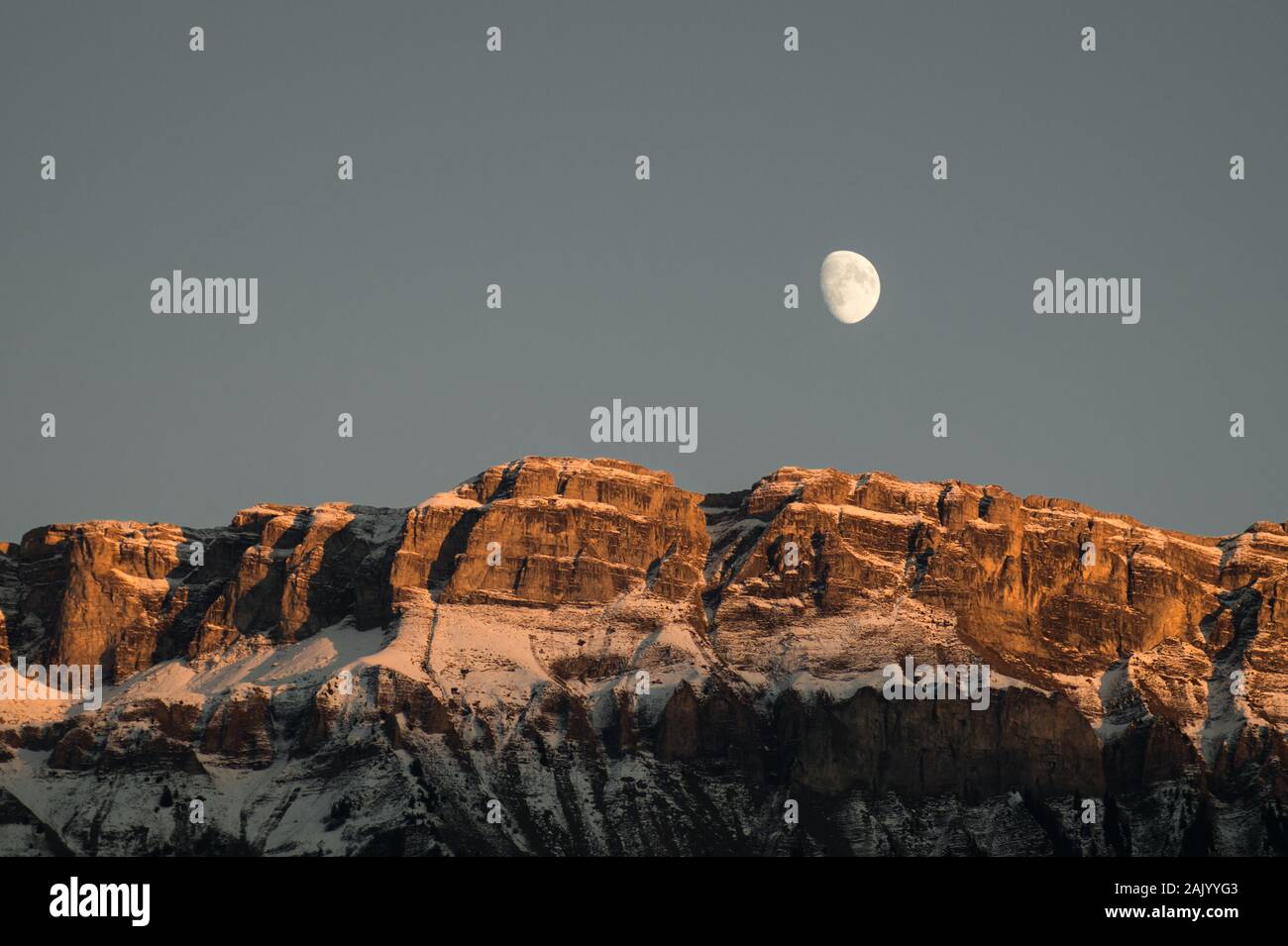 Lune blanche au-dessus une impressionnante gamme de montagne en Suisse pendant l'heure d'or Banque D'Images