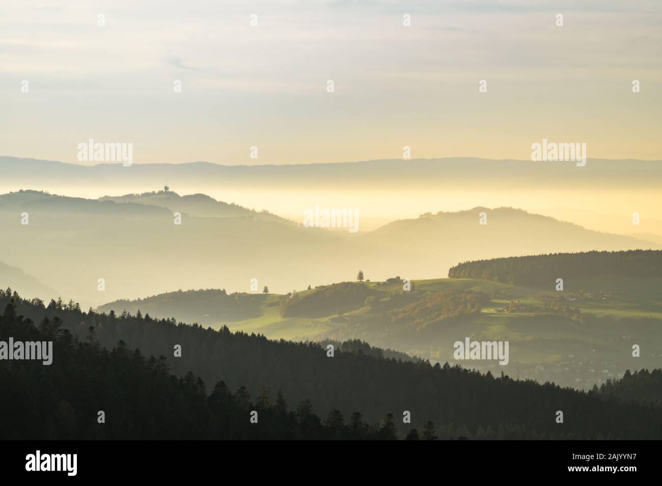 Village couvert dans le brouillard pendant le coucher du soleil avec une lumière chaude et une tour de diffusion à l'arrière-plan Banque D'Images