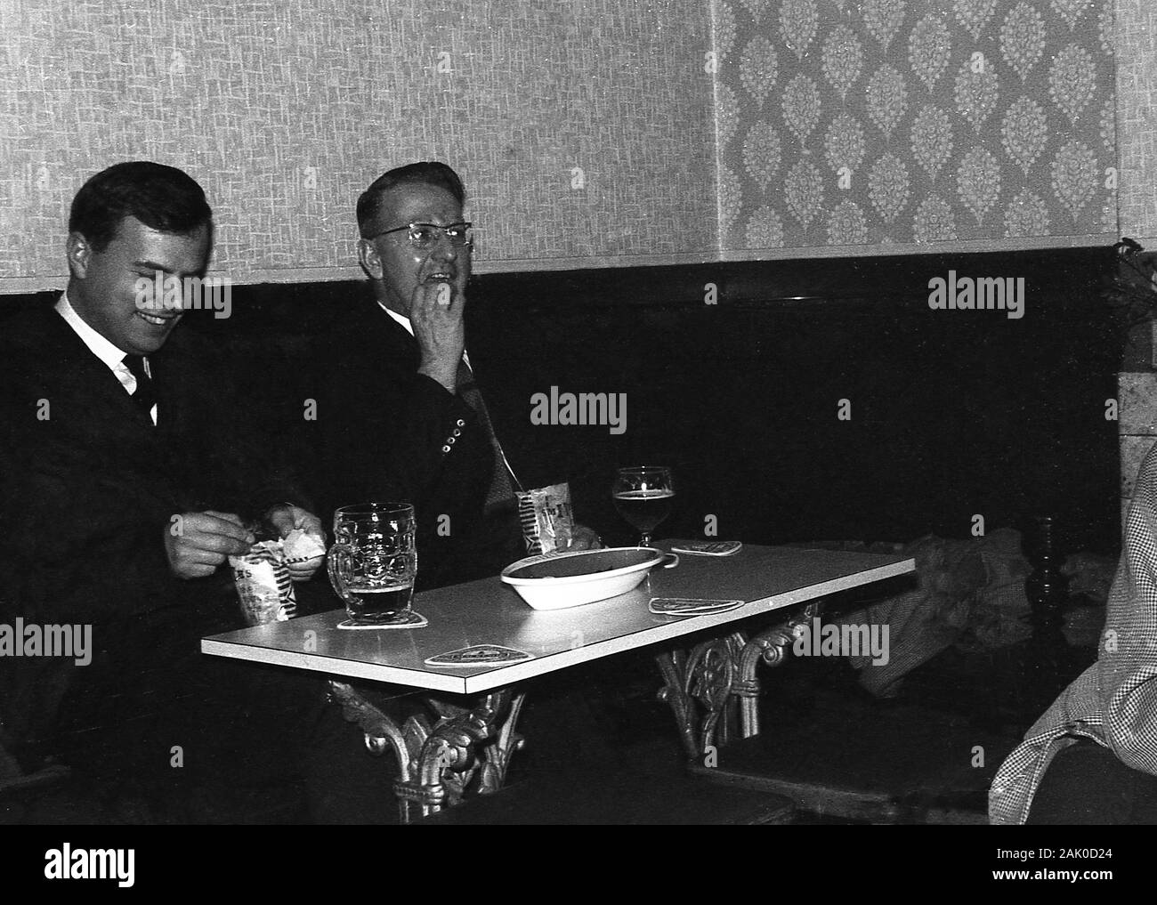 Années 1960, historiques, deux hommes bien habillés bénéficiant d'une bière et des chips de pommes de terre assis à une table dans un coin d'un bar ou pub, England, UK. Banque D'Images
