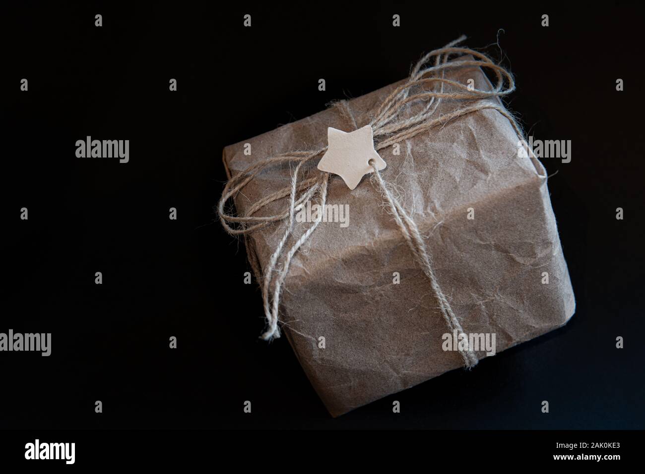 Boîte cadeau en papier artisanal sur fond noir avec étoile au centre pour étiquette ou texte Banque D'Images