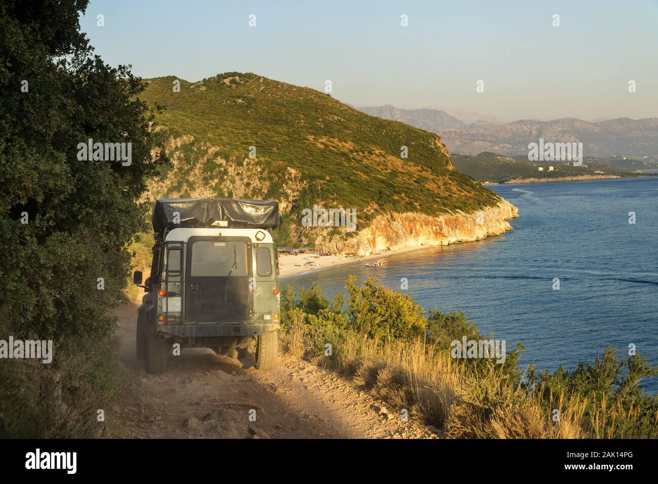 4x4 hors route voiture avec tente sur le toit se déplace le long d'un chemin de terre au-dessus du précipice vers la plage de Gjipe gorge en Albanie en été au coucher du soleil. Banque D'Images