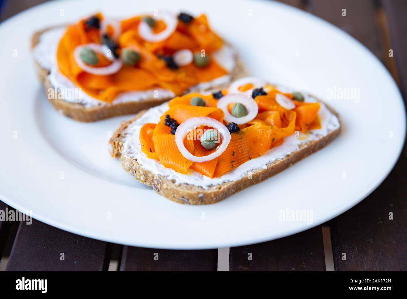 Carotte Vegan végétalien lox - Saumon fumé basé sur les carottes qui est servi sur un pain au levain surmontée d'oignons, de câpres et de caviar d'algues vegan Banque D'Images Carotte Vegan végétalien lox - Saumon fumé basé sur les carottes qui est servi sur un pain au levain surmontée d'oignons, de câpres et de caviar d'algues vegan Banque D'Images