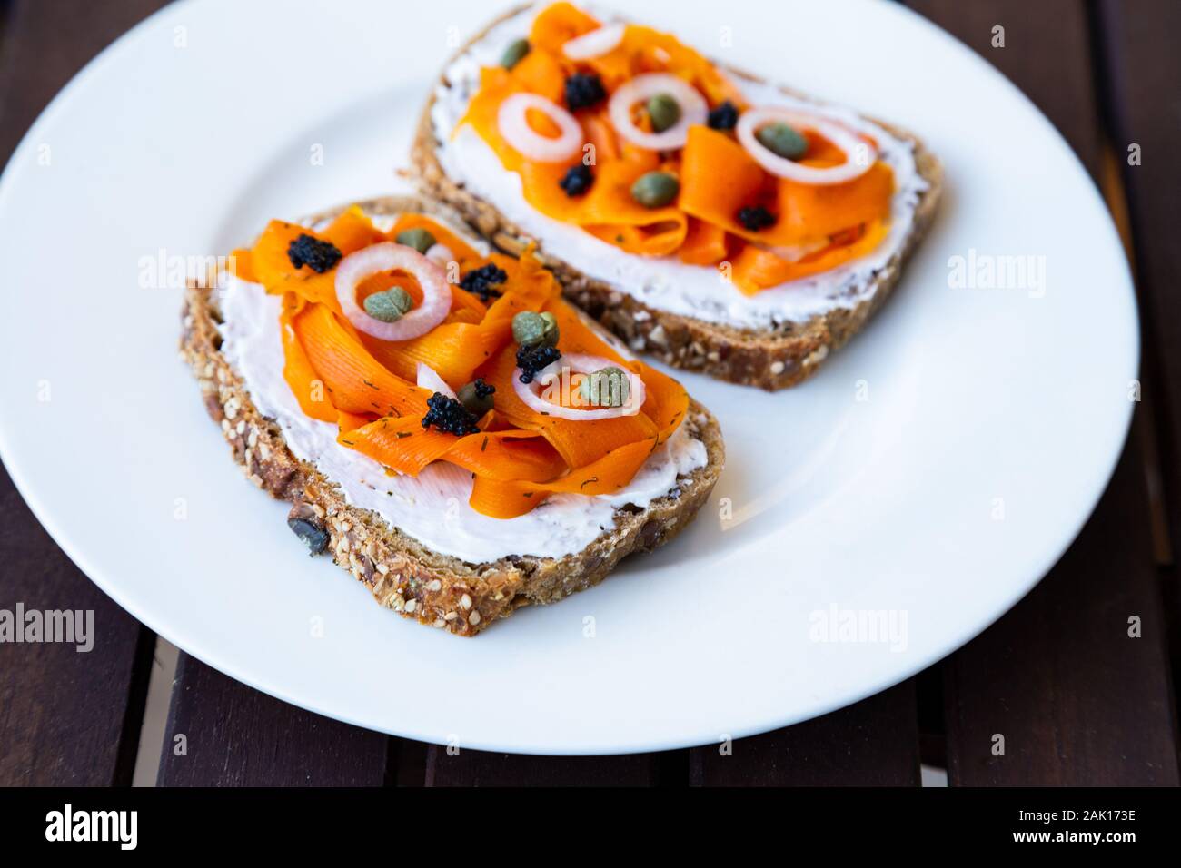 Carotte Vegan végétalien lox - Saumon fumé basé sur les carottes qui est servi sur un pain au levain surmontée d'oignons, de câpres et de caviar d'algues vegan Banque D'Images Carotte Vegan végétalien lox - Saumon fumé basé sur les carottes qui est servi sur un pain au levain surmontée d'oignons, de câpres et de caviar d'algues vegan Banque D'Images
