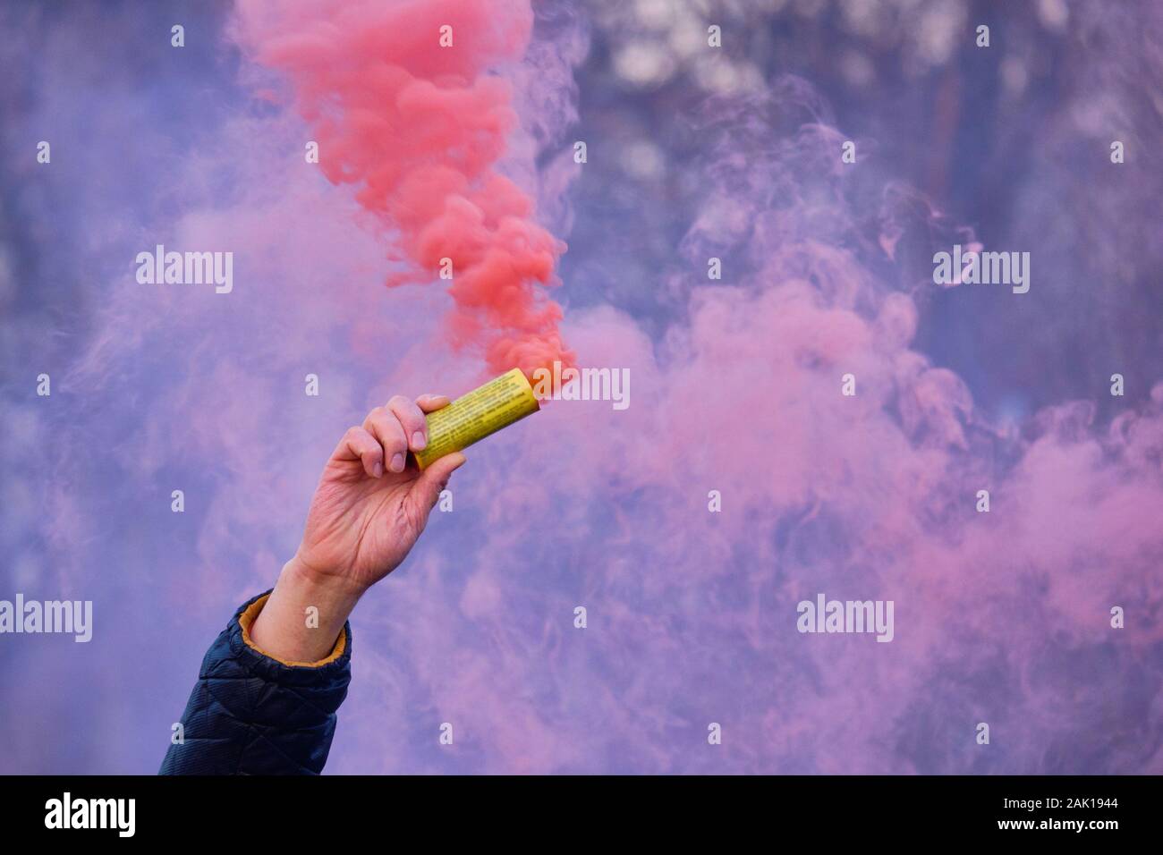 La main est titulaire d'un artifice avec une fumée de la couleur de rose. Close up. Banque D'Images