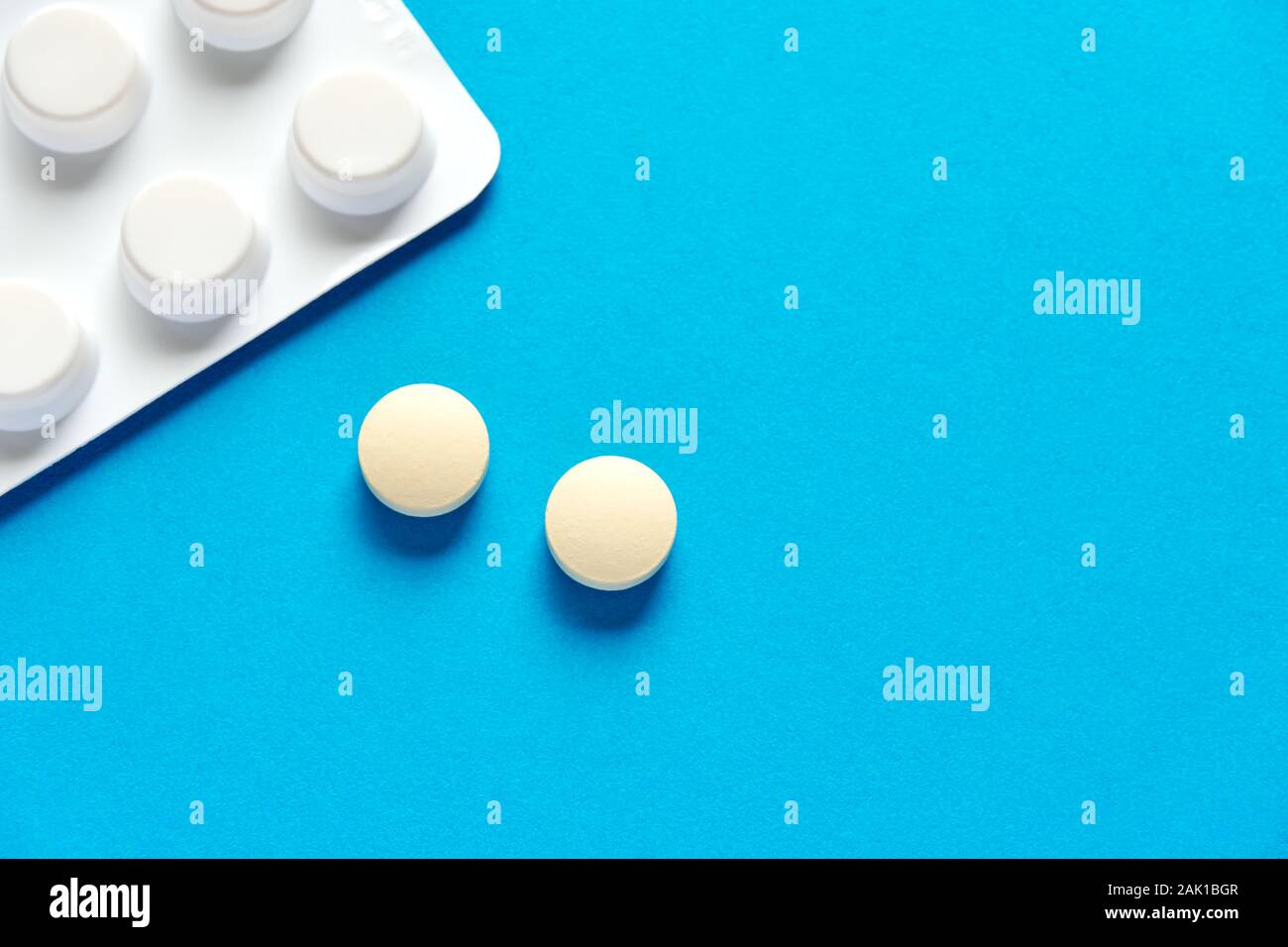 Deux comprimés ou pilules à prescription ronde et blanche et une bande de pilules sur fond bleu ou sarcelle avec un espace de copie à utiliser comme modèle Banque D'Images