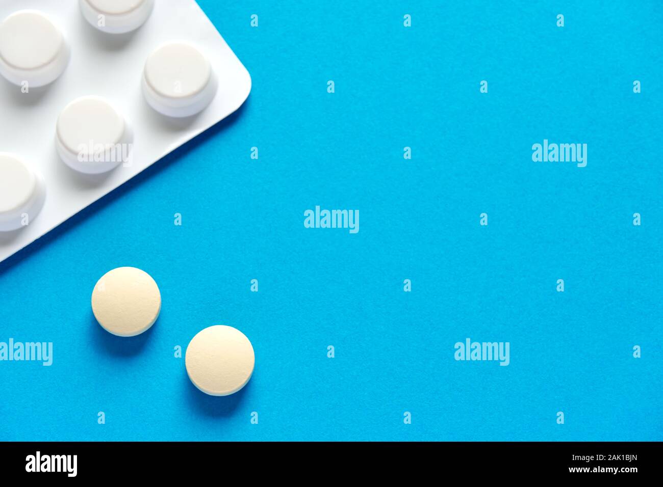 Deux comprimés ou pilules à prescription ronde et blanche et une bande de pilules sur fond bleu ou sarcelle avec un espace de copie à utiliser comme modèle Banque D'Images