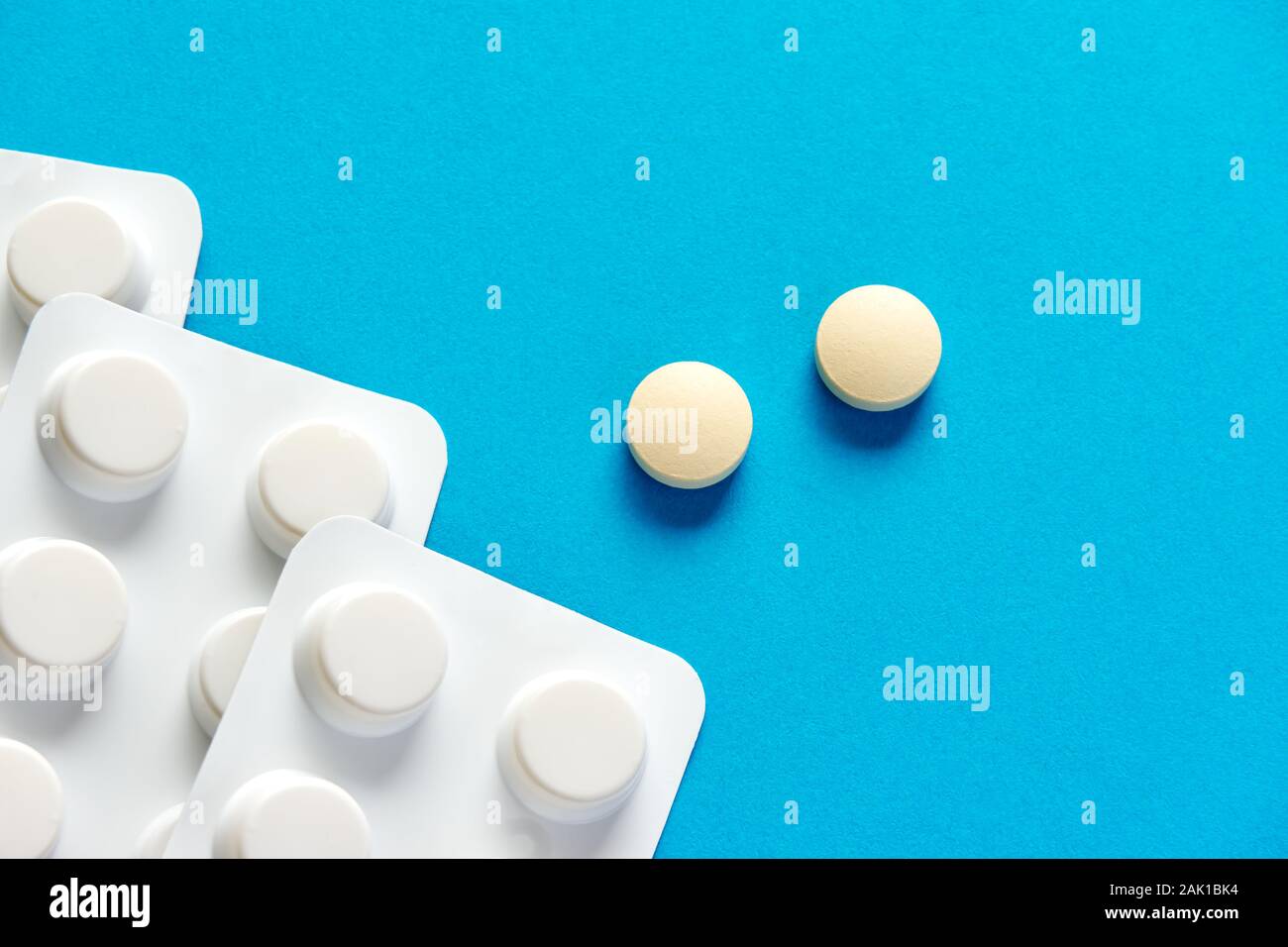 Deux comprimés ou pilules à prescription ronde et blanche et une bande de pilules sur fond bleu ou sarcelle avec un espace de copie à utiliser comme modèle Banque D'Images