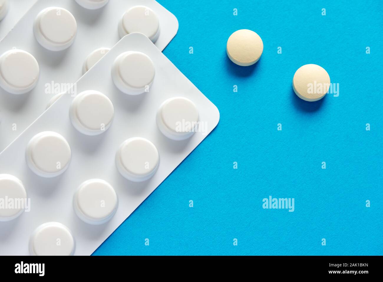 Deux comprimés ou pilules à prescription ronde et blanche et une bande de pilules sur fond bleu ou sarcelle avec un espace de copie à utiliser comme modèle Banque D'Images