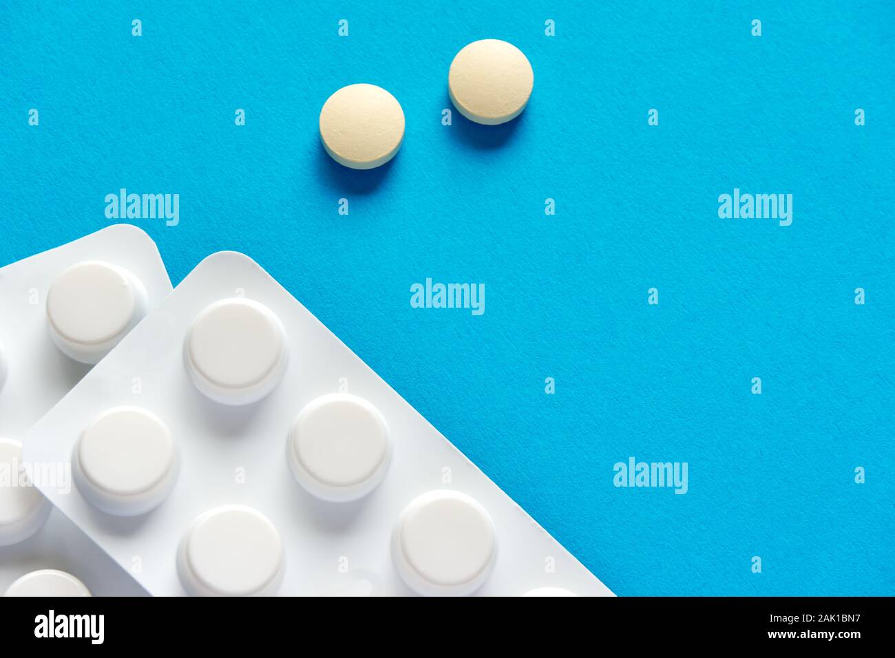 Deux comprimés ou pilules à prescription ronde et blanche et une bande de pilules sur fond bleu ou sarcelle avec un espace de copie à utiliser comme modèle Banque D'Images