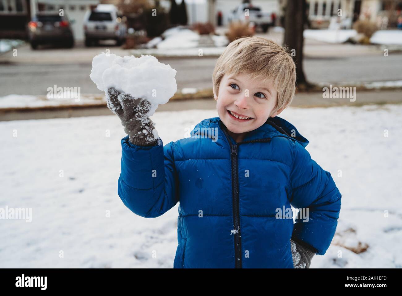 Un petit garçon tient un boule de neige. Banque D'Images