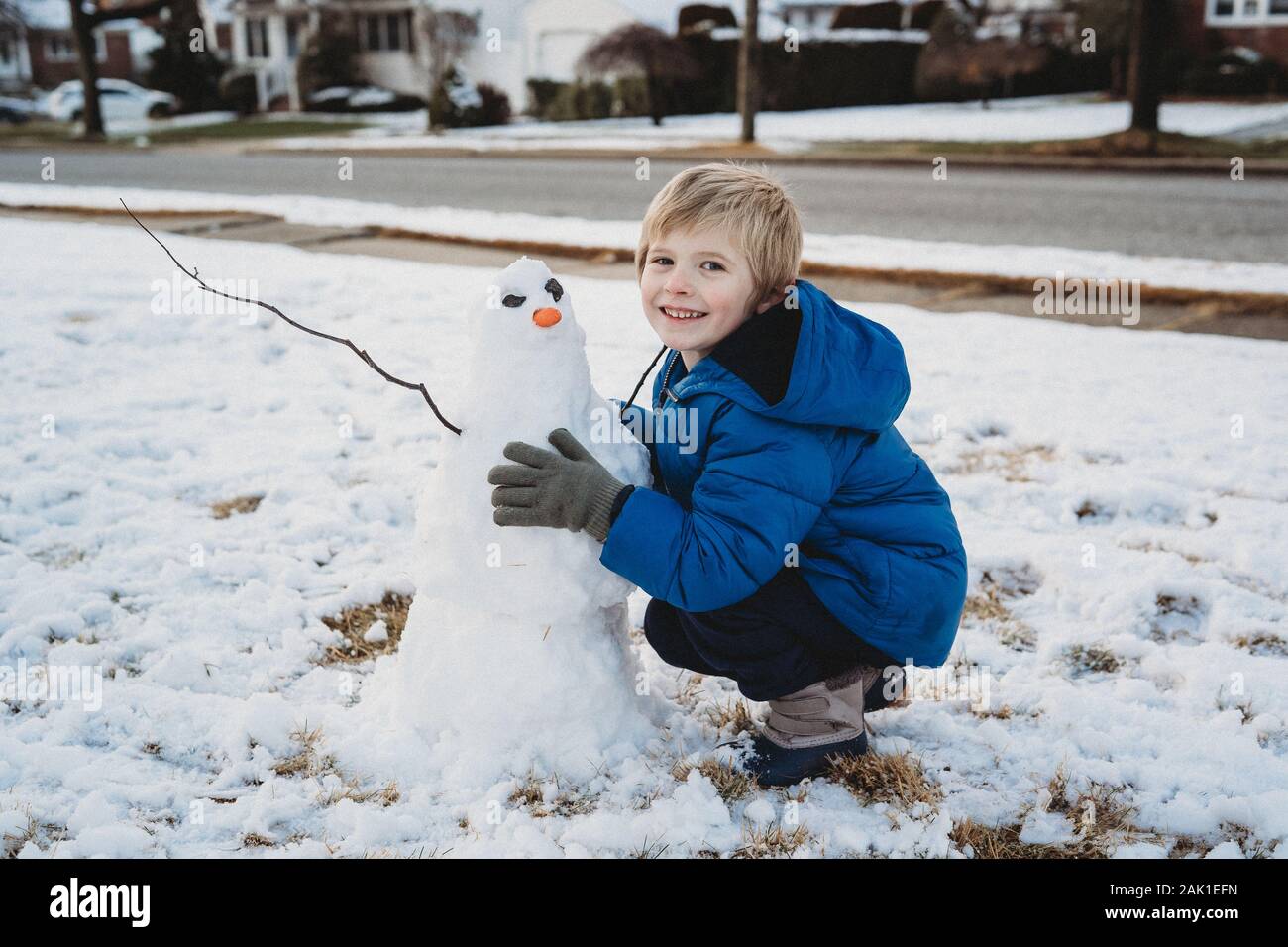 Un petit garçon construit un bonhomme de neige. Banque D'Images